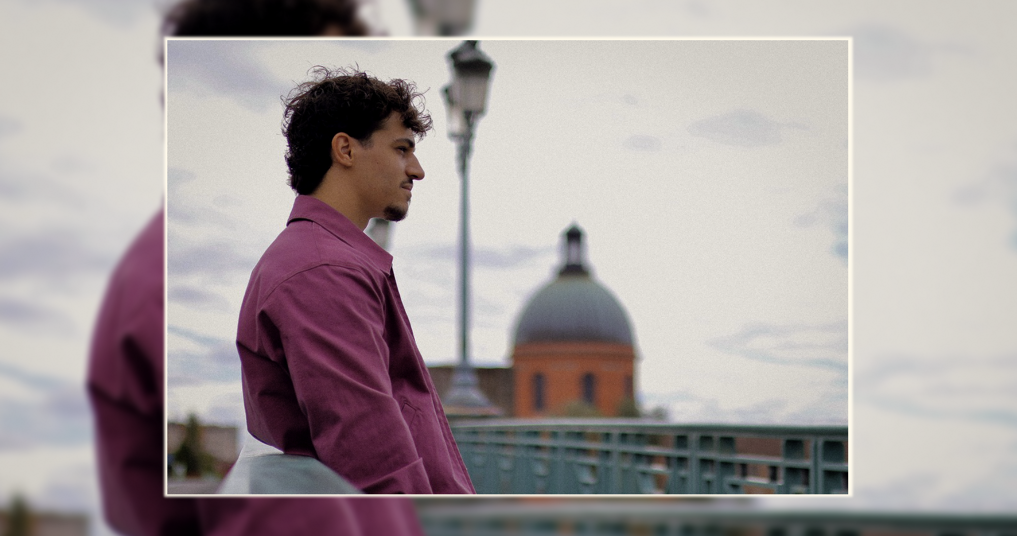 Portrait urbain sur pont – Lumineo Homme en extérieur sur un pont avec un dôme architectural en arrière-plan – portrait urbain par Luminéo