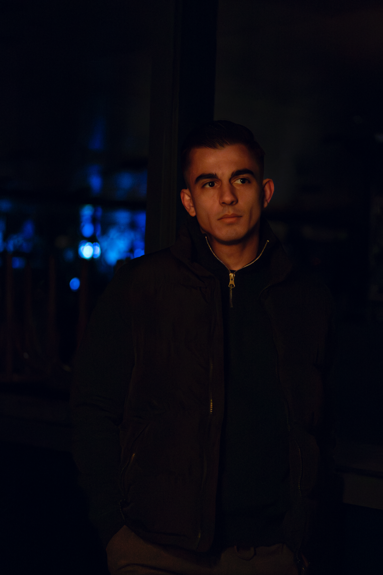 Jeune homme neutre devant une porte bleue - photographie Night shoot par luminéo