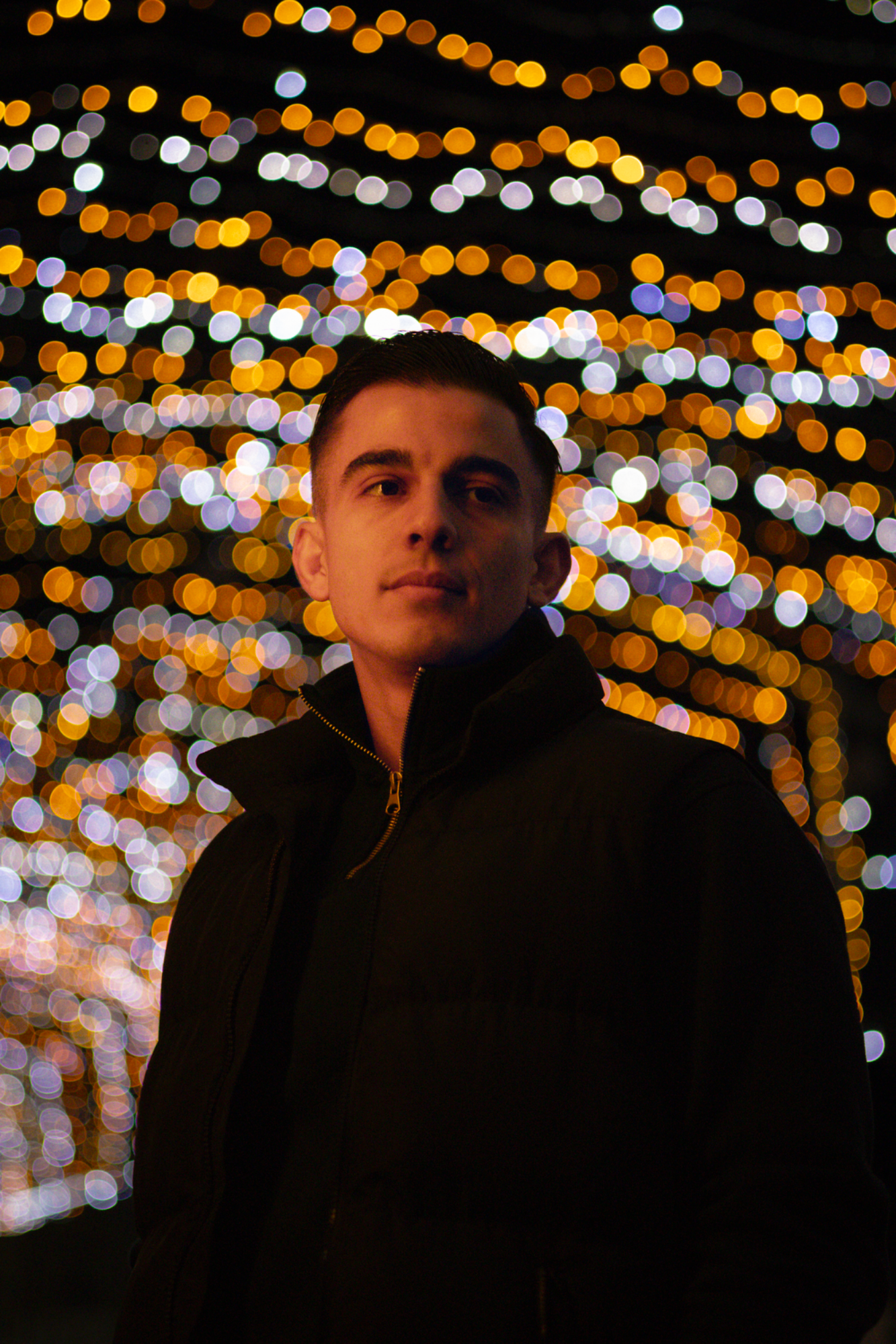Jeune homme pensif sous une guirlande en hivers en extérieur de nuit – photographie Night shoot par luminéo