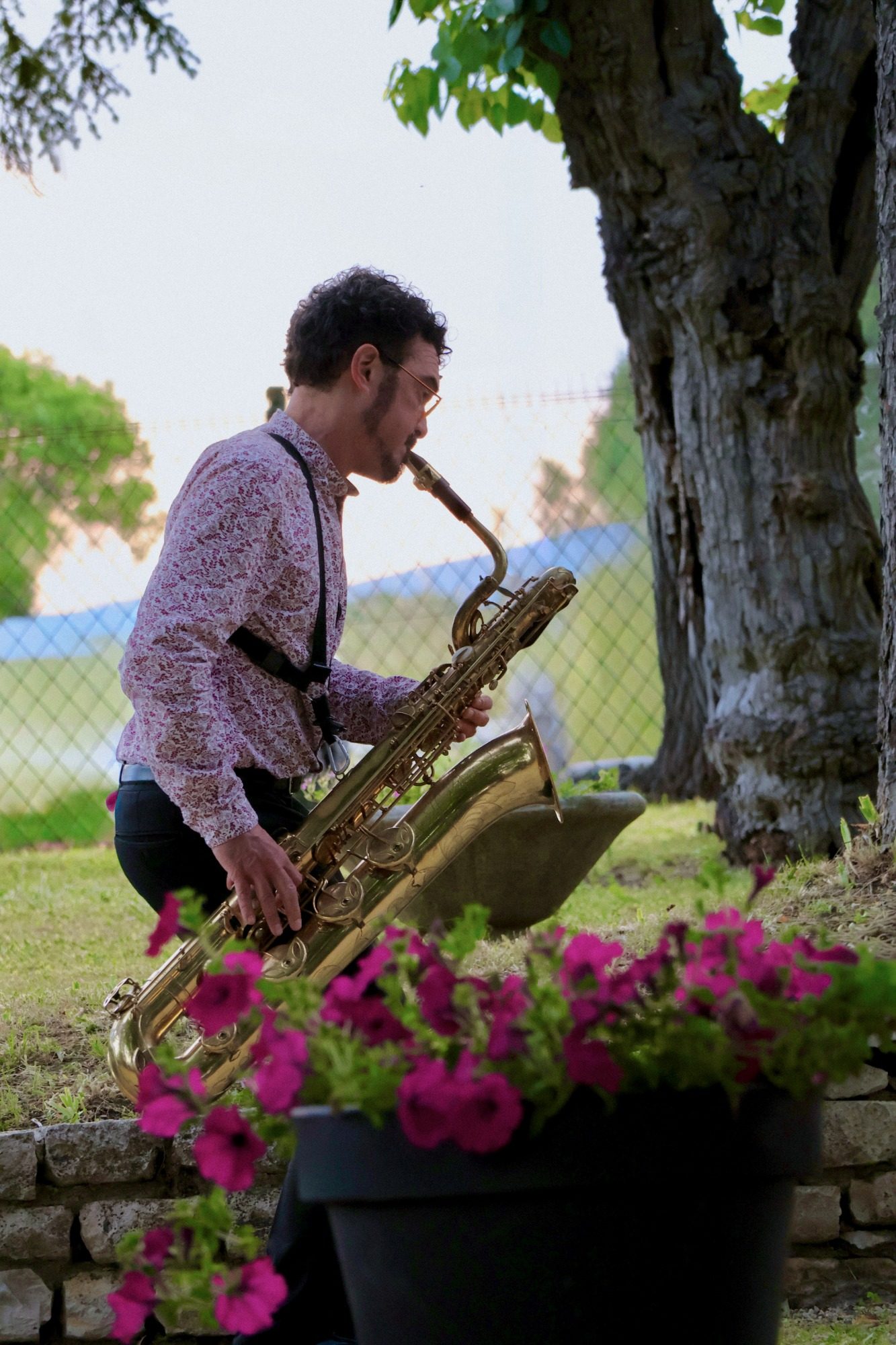 Musicien jouant du saxophone en extérieur près d’un arbre, ambiance chaleureuse – photographie événementielle par Luminéo