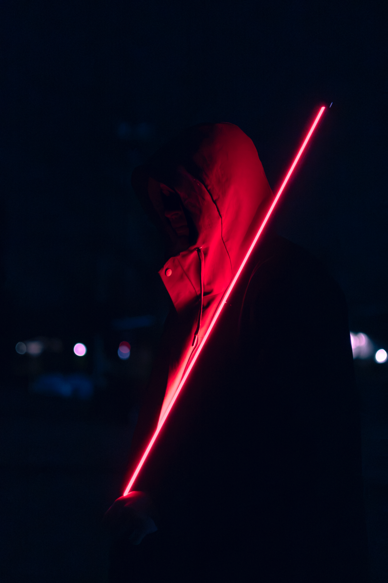 Jeune homme mystérieux de nuit portant une lumière rouge sur le bras – photographie Night shoot par luminéo